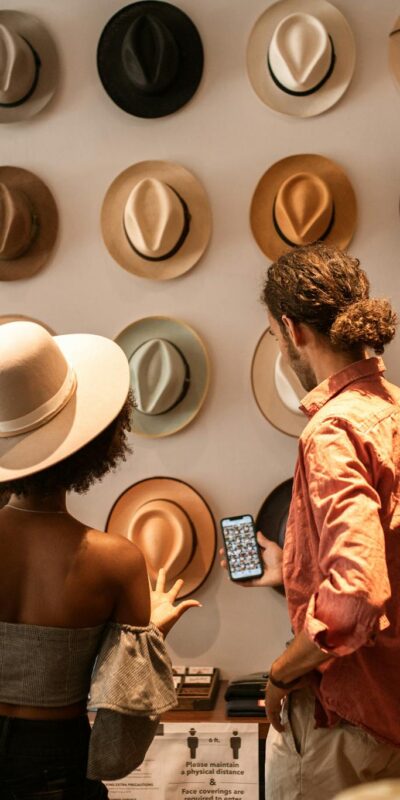 A stylish couple exploring a hat boutique, showcasing diverse headwear.