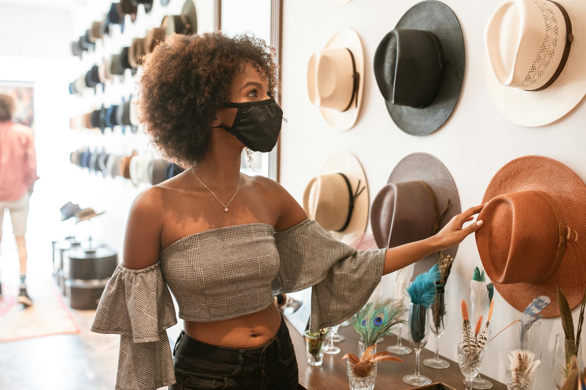 A woman explores stylish hats in an indoor boutique, embracing fashion trends.