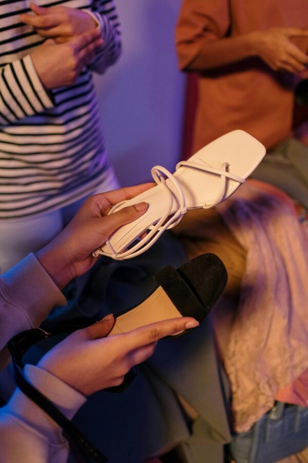Close-up of stylish sandals held in hand, showcasing modern footwear fashion.