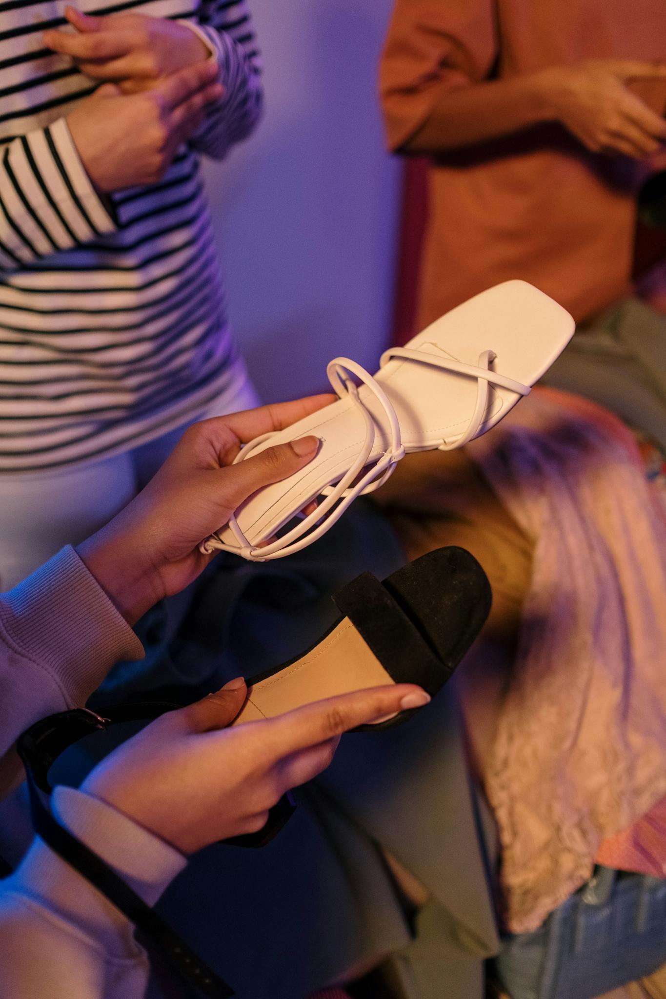 Close-up of stylish sandals held in hand, showcasing modern footwear fashion.