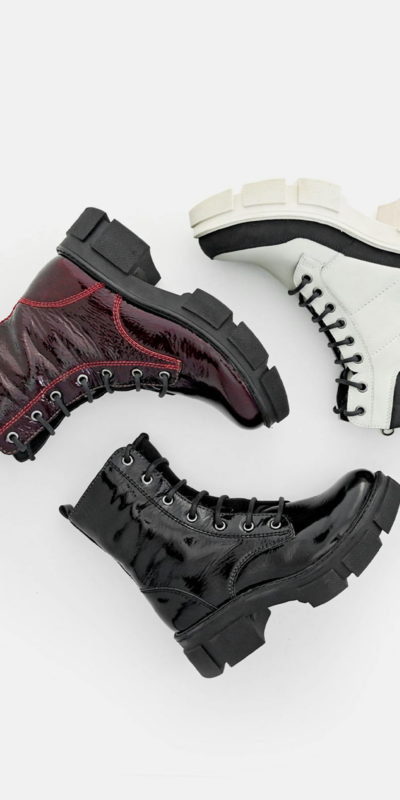 Stylish leather lace-up boots in black, white, and red on a white background.